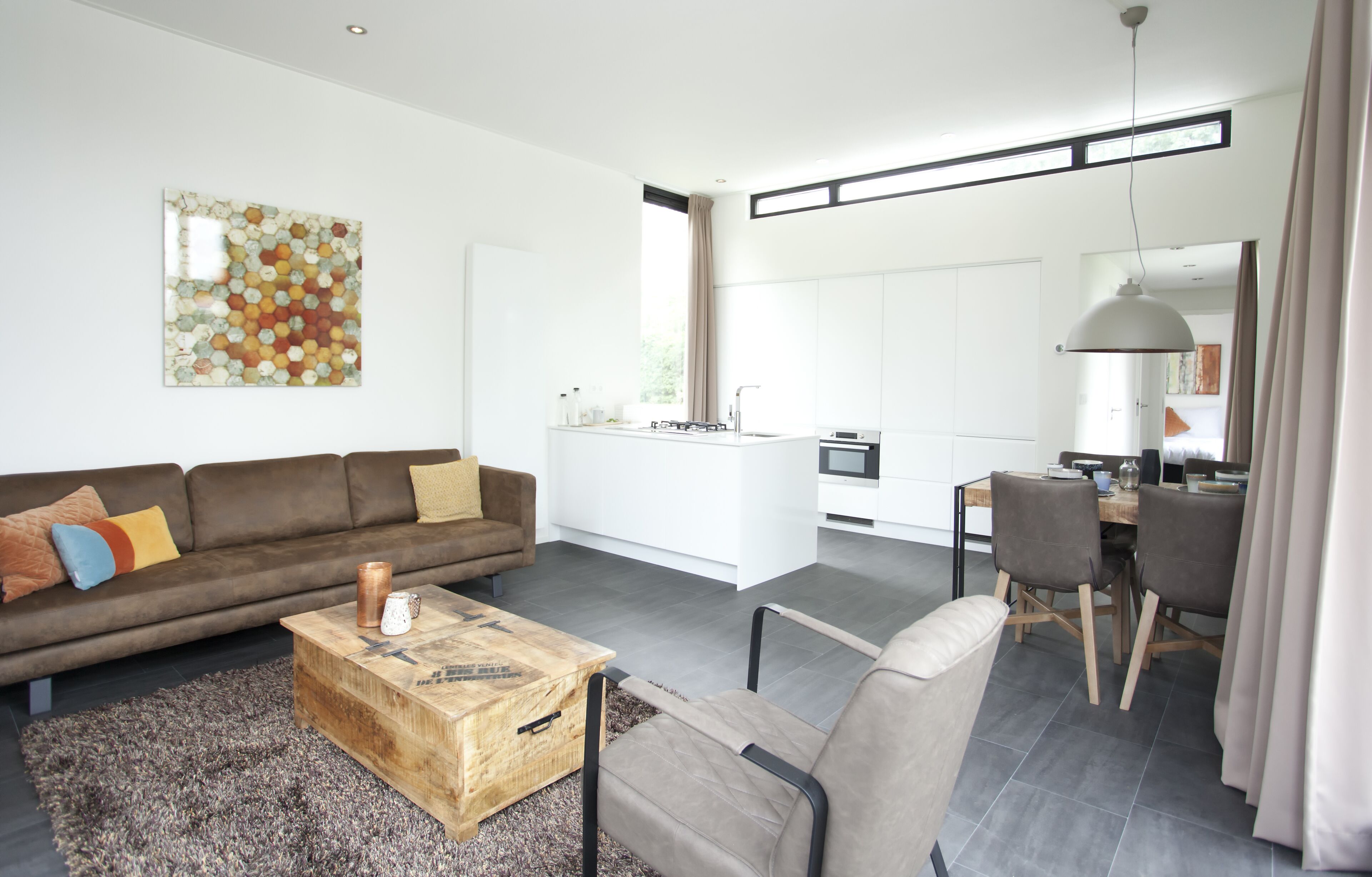 A modern living room with a brown sofa, wooden coffee table, and a large abstract painting.