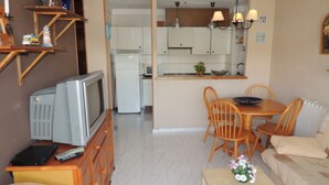 A compact living space with a kitchenette, a dining area, and a seating area with a sofa and chairs. - JARDINS III 412 Roses (Rosas / Roses)