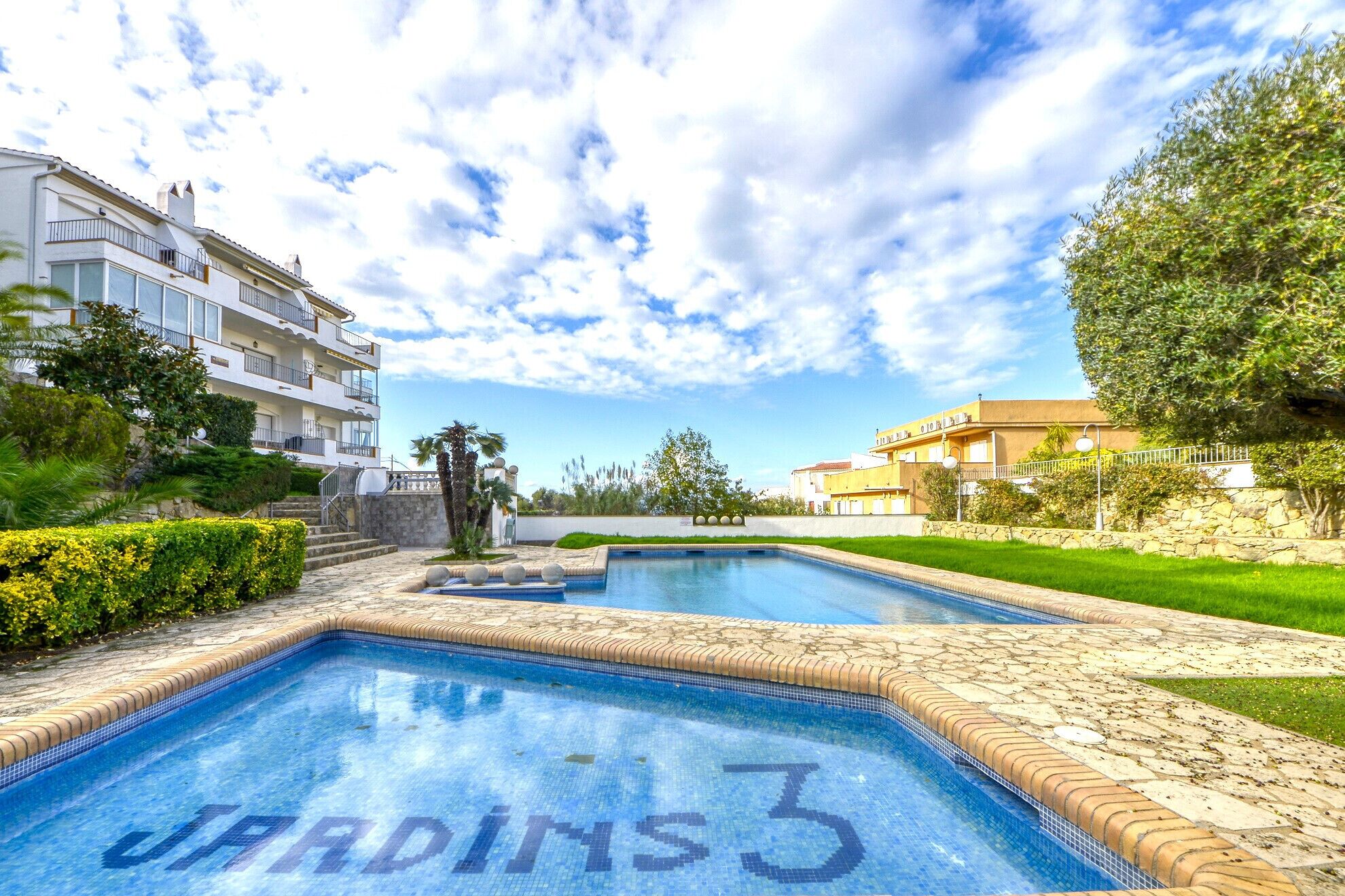 A swimming pool with a tiled border and a clear blue sky.