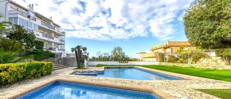 A swimming pool with a tiled border and a clear blue sky.