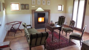 Ein Wohnzimmer mit Kamin, einem gemusterten Teppich und mehreren gerahmten Pflanzenbildern an der Wand.
