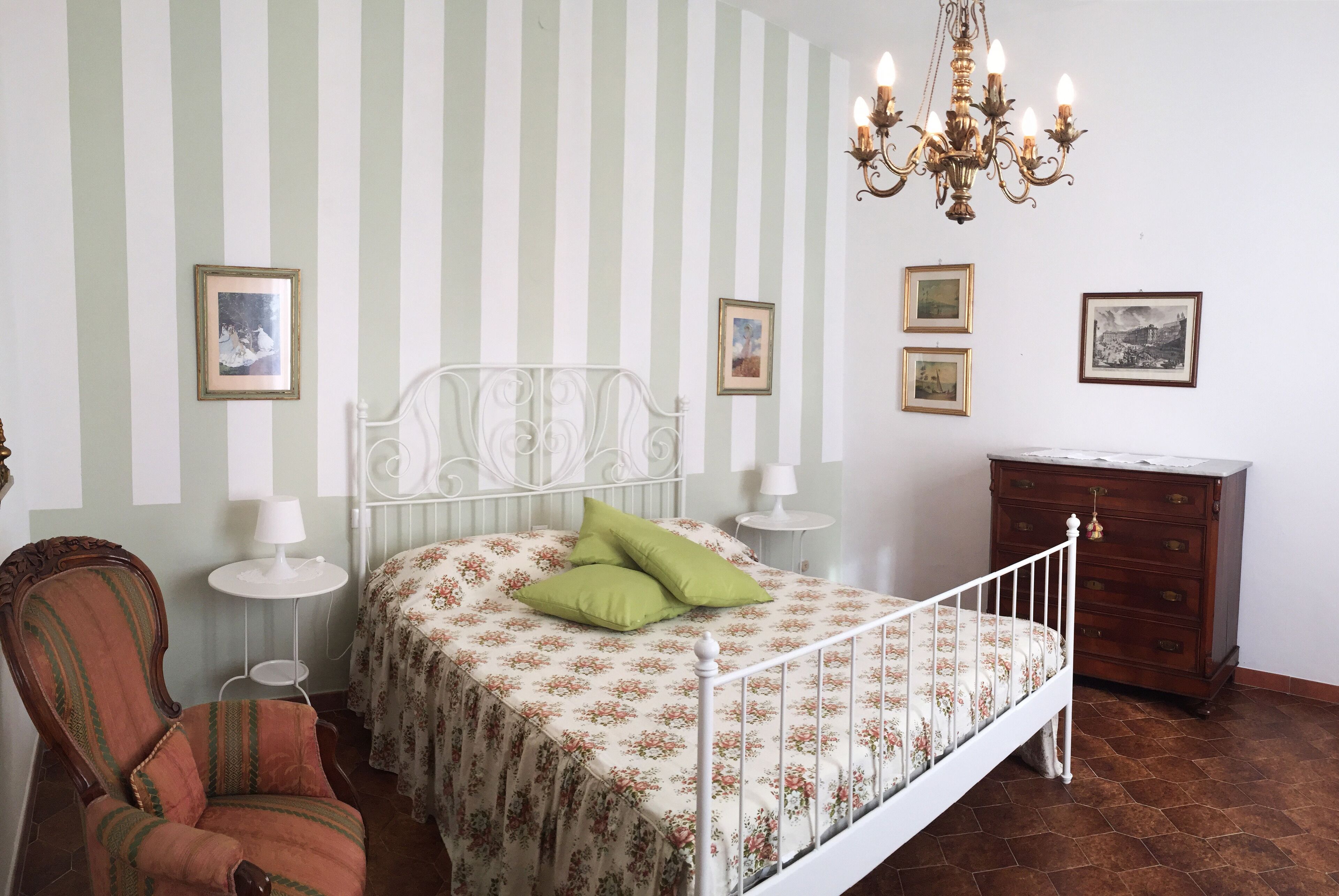 Une chambre à coucher avec un lit, une chaise, une commode et un lustre.