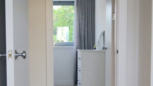 A narrow hallway with wooden flooring leading to a bathroom with a window and a towel rack. - NEW! Luxury Apartment in Truro Centre With Cathedral Views! (Truro)