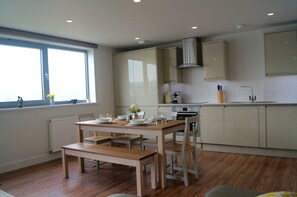 Una cocina moderna con armarios de madera, una mesa de comedor preparada para cuatro personas y un ventanal que proporciona luz natural.