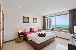 A modern hotel room with a large bed, a view of the ocean, and a desk with a computer. - Tranquil Residence 3 (Koh Samui)