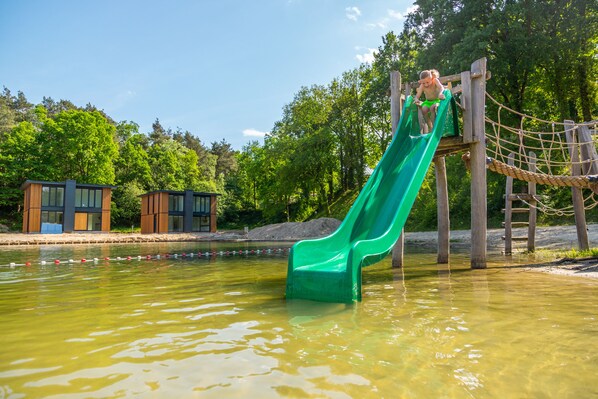 A water slide in a park with wooden structures and a small building in the background. - EuroParcs Maasduinen (Belfeld)