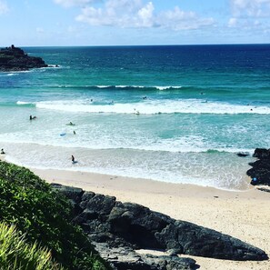 A beach with clear turquoise waters, waves, and a rocky shoreline. - Stylish central St Ives Townhouse, Sea Views, Garden, Parking, Walk to beaches (St. Ives)