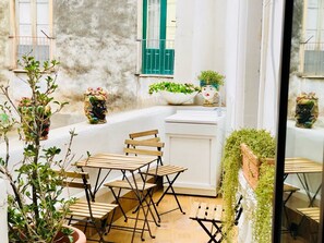 A small, cozy outdoor seating area with wooden tables and chairs, surrounded by potted plants and decorative items. - I Lumi (Catania)