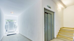 A hallway with a door leading to an elevator and a staircase. - PUIG ROM 115 1 2  Roses (Rosas / Roses)