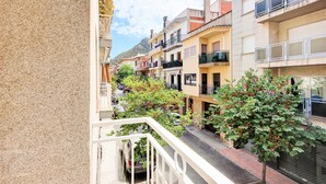 A narrow street with multi-story buildings, balconies, and parked cars. - PUIG ROM 115 1 2  Roses (Rosas / Roses)