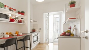 A modern kitchen with white cabinets, a built-in oven, and a dining area with two black chairs. - Central, next to the Metro, overlooking the famous Appia Antica Park (Roma)