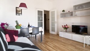 A modern living room with a sofa, dining table, and TV. - Central, next to the Metro, overlooking the famous Appia Antica Park (Roma)