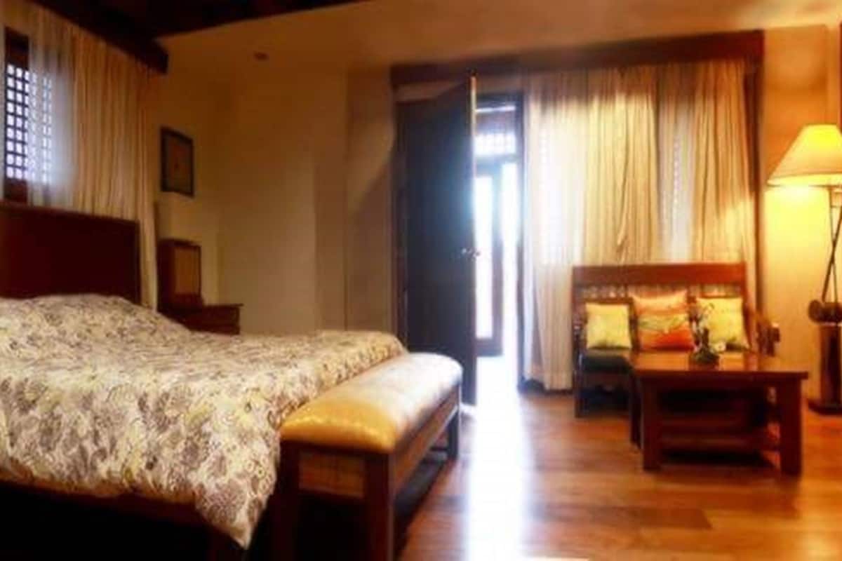 Une chambre d’hôtel comprenant un lit, un bureau, une chaise, une lampe et un téléviseur.