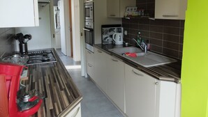A kitchen with a gas stove, a sink, and cabinets.