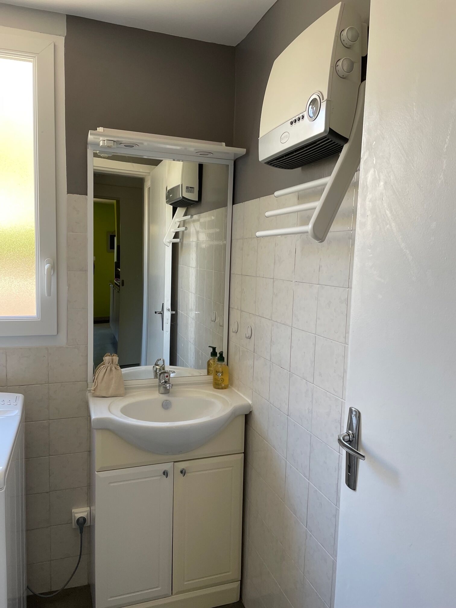 Ein Badezimmer mit einem weißen Waschbecken, einem Spiegel und einem Handtuchhalter.