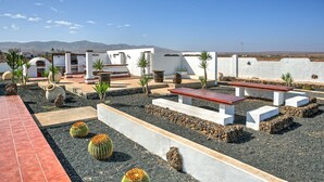 A rooftop garden with a seating area, cacti, and a view of distant mountains. - Villa the path of the majorero (Antigua)