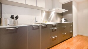 A modern kitchen with stainless steel appliances, white cabinetry, and a wooden floor.