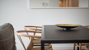 A dining area with a table and chairs, a bowl on the table, and a woven throw on a chair.