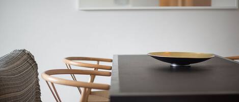 Un comedor con una mesa y sillas, un cuenco sobre la mesa y un plaid tejido en una silla.