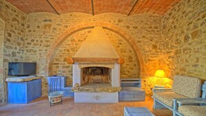 A stone-walled room with a fireplace, a television, and seating. - Lovely apartment for 6 people with A/C, pool, WIFI, TV and panoramic view, close to San Gimignano (Poggibonsi)