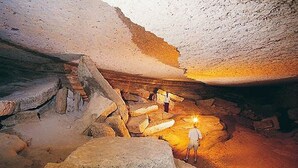 A cave with a person holding a light, examining the rocky formations.