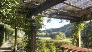 Una pérgola de madera con una mesa de picnic en un jardín.