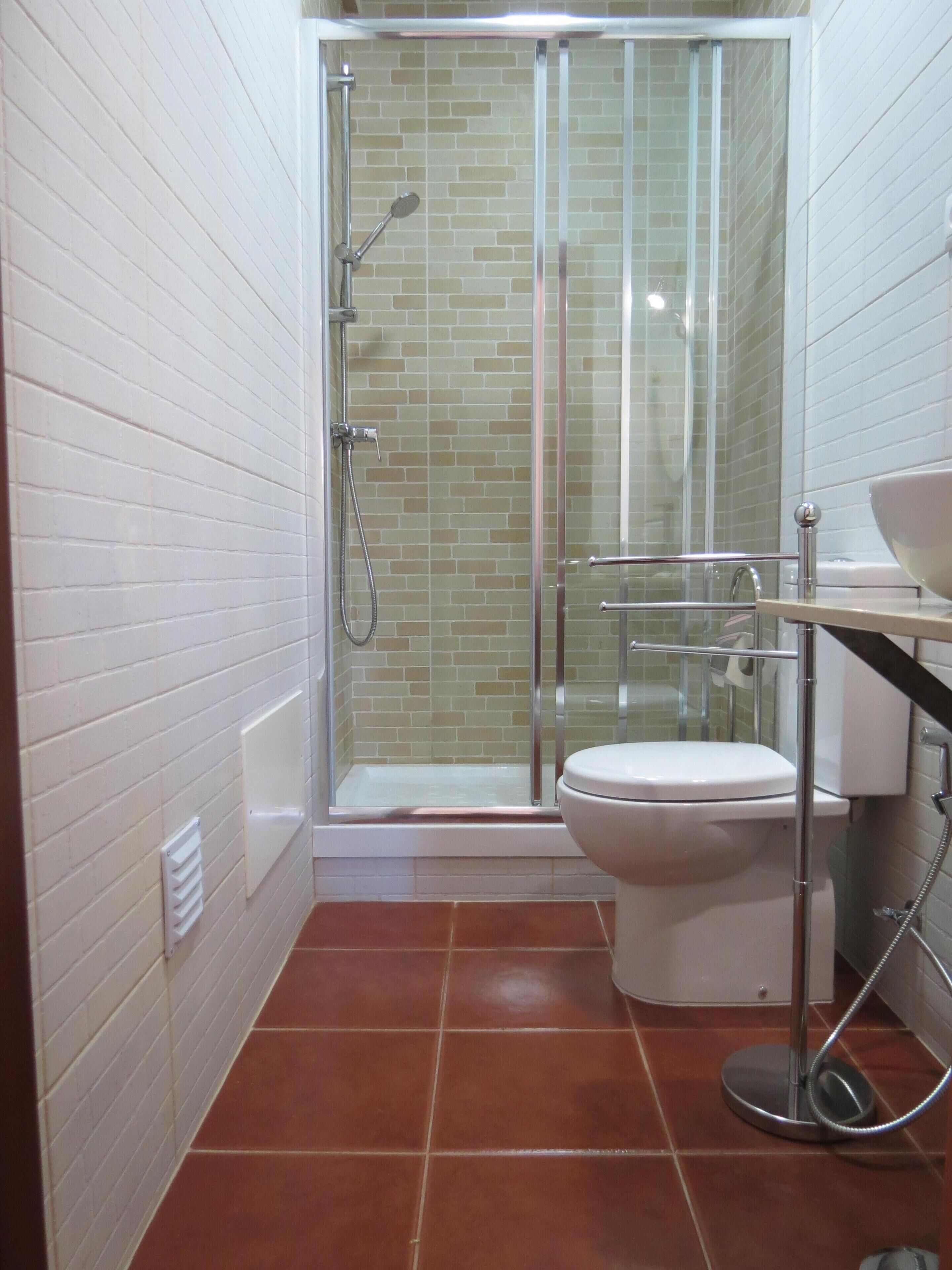 A bathroom with a glass-enclosed shower, a toilet, and a sink.