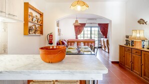 A kitchen with a large orange bowl, a dining table set with plates and glasses, and a wooden cabinet.