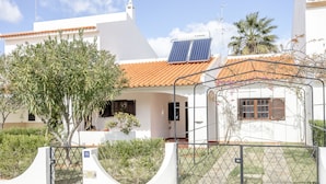 A white building with a tiled roof, solar panels, and a gated entrance.