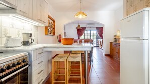 A kitchen with a central island, wooden stools, a stove, and a refrigerator.