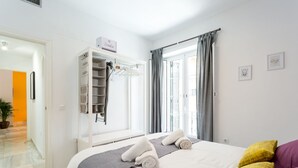 Une chambre d’hôtel avec un lit, une armoire, une fenêtre avec des rideaux et une petite plante.