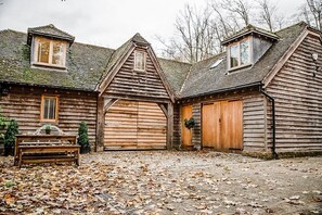 A rustic wooden building with a large central door, a smaller door on the right, and a window on the left.