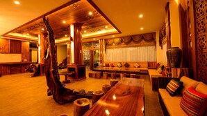 Un vestíbulo espacioso con un mostrador de recepción de madera, una gran escultura de madera y una zona de estar con sofás y una mesa larga.