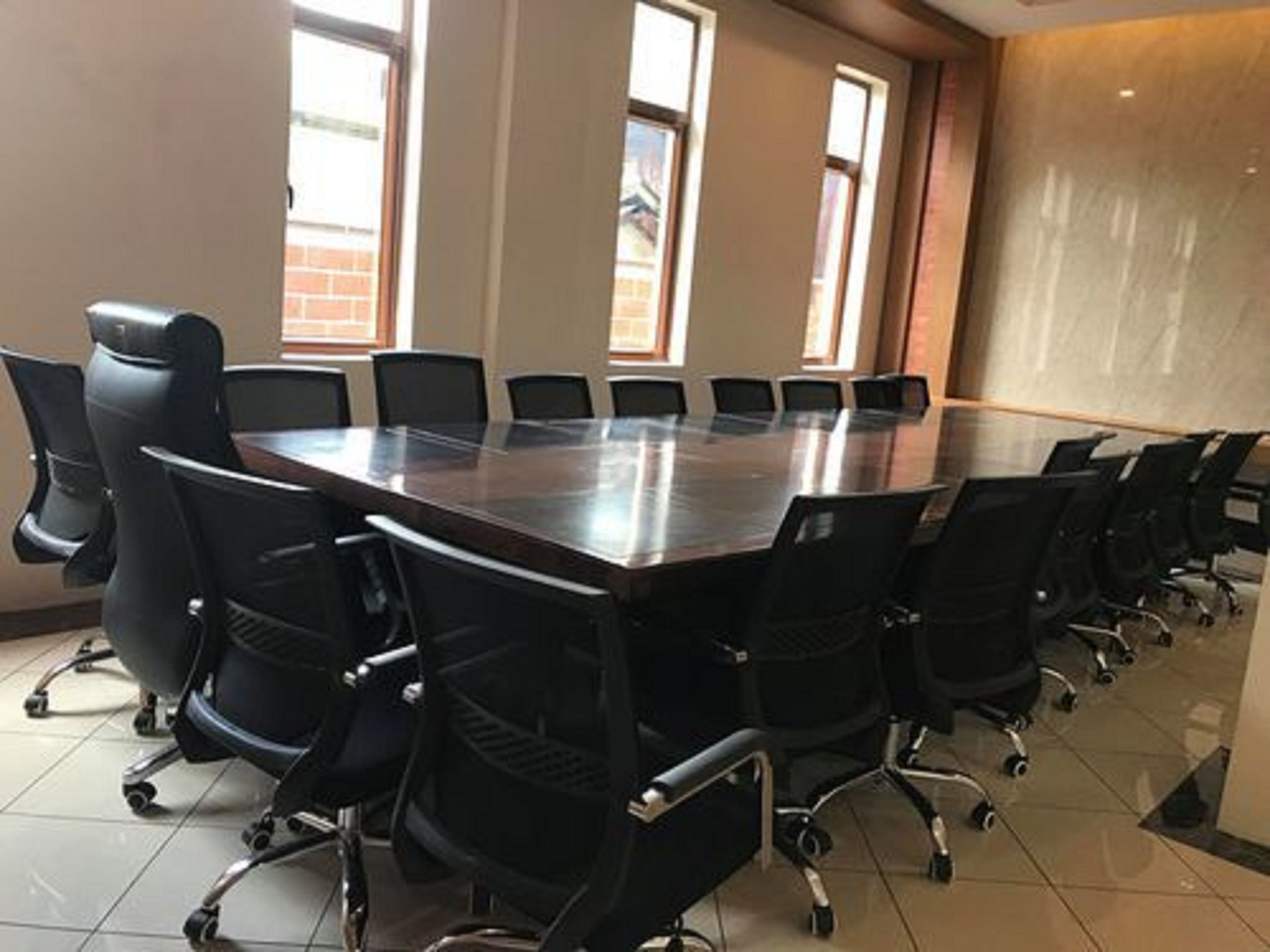 A conference room with a large rectangular table surrounded by black chairs with wheels.