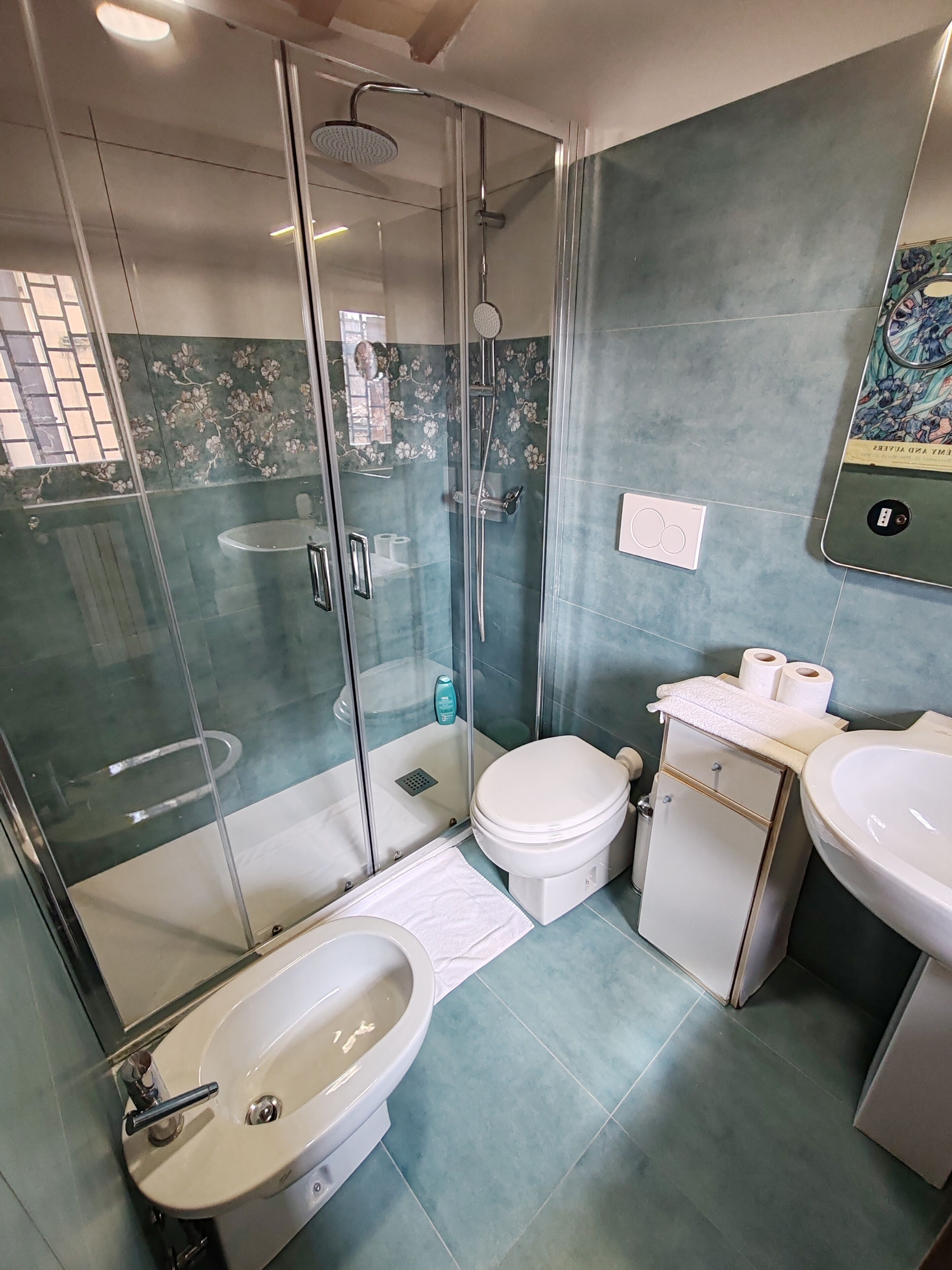 A modern bathroom with a glass-enclosed shower, a white sink, a toilet, and a vanity with a mirror.