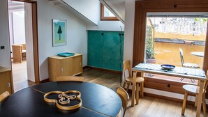 A dining area with a round table, chairs, and a view of the outside through a large window. - Attic of great charm with terraces and panoramic views (Roma)