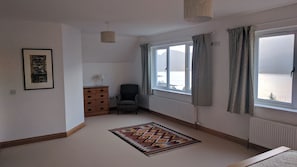 Enjoy a serene view of the snowy landscape from the comfort of this cozy room, featuring a large window, a dresser, and a plush rug.