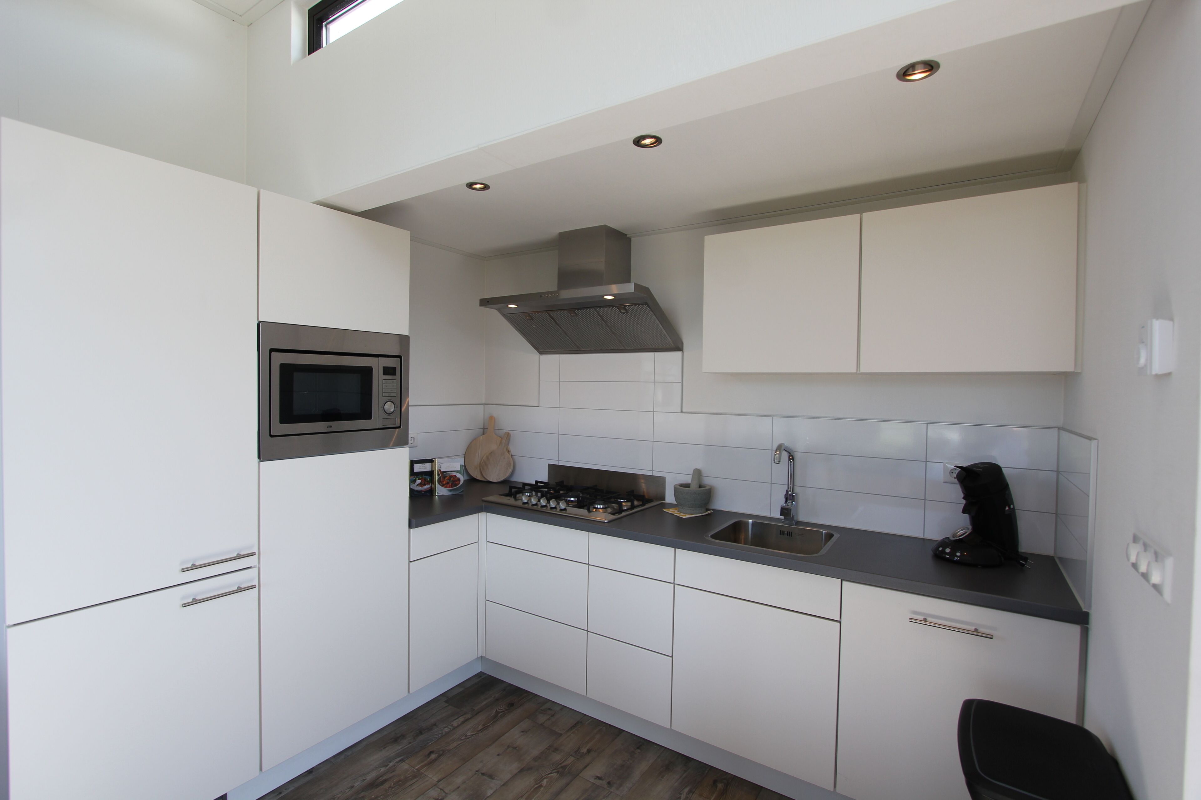 A compact kitchen with white cabinets, a microwave, a stove, and a sink.