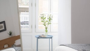 A bedroom with a bed, a small table with a plant, and a window with a view of a balcony. - Singular Stays Mar44 III (Valencia ciudad)