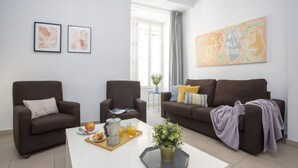 A modern living room with two sofas, a coffee table with breakfast items, and abstract wall art. - Singular Stays Mar44 III (Valencia ciudad)