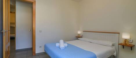Una habitación de hotel con una cama, dos lámparas de noche, una puerta de madera y una mesita auxiliar.