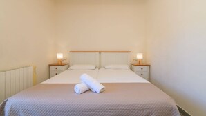 A single bed with two bedside tables, a headboard, and two lamps.