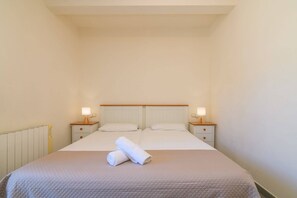 A single bed with two bedside tables, a headboard, and two lamps.