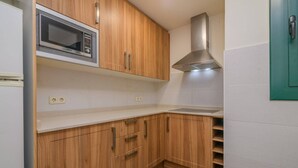 A kitchen with wooden cabinets, a microwave, a stainless steel range hood, and a white countertop.
