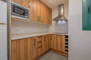 A kitchen with wooden cabinets, a microwave, a stainless steel range hood, and a white countertop.