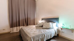 Ein Schlafzimmer mit Bett, Vorhängen, einem Nachttisch und einem Beistelltisch.