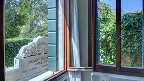 Et vindue med udsigt til grøn bevoksning og en plade med teksten "PEGGY GUGGENHEIM COLLECTION".