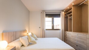 A bedroom with a bed, bedside table, and a walk-in closet. - ApartUP Mestalla Home (Valencia)