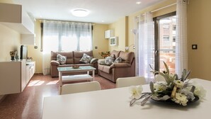 A living room with two sofas, a dining table, and a kitchen area. - ApartUP Mestalla Home (Valencia)