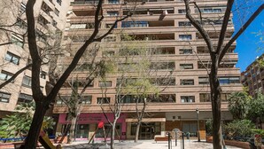 A multi-story residential building with balconies, a playground with swings and a climbing structure, and a street with trees and benches. - ApartUP Mestalla Home (Valencia)